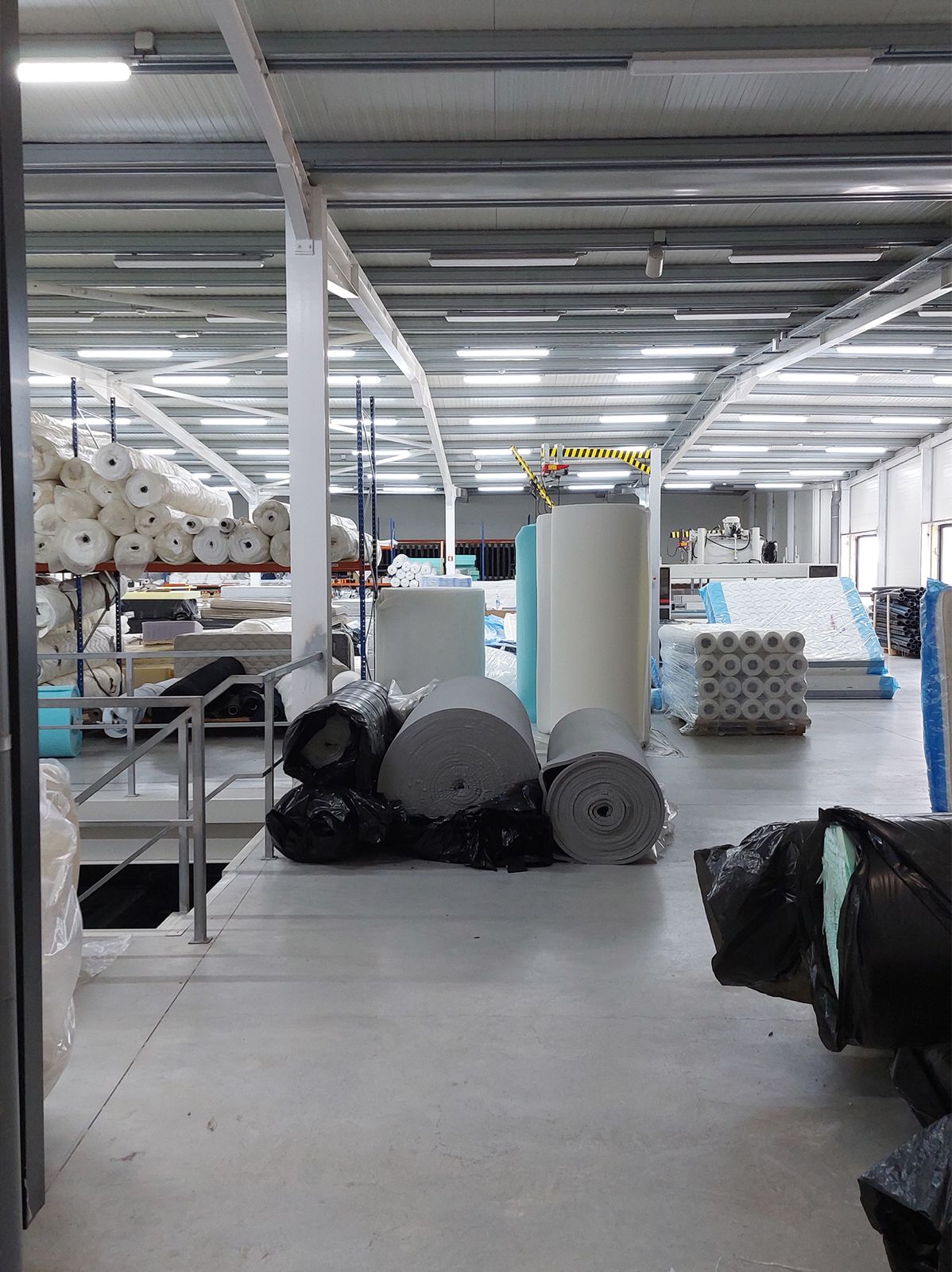 Interior da fábrica Noites Tranquilas, com rolos de tecido e espuma